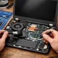 Technician performing professional laptop maintenance by cleaning internal components, fans, and RAM modules using precision tools and isopropyl alcohol.
