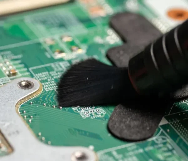 Close-up of a technician using a soft brush to clean a laptop motherboard as part of professional laptop repair and internal cleaning services.
